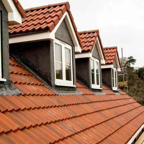 Newly built roof with windows and scaffolding erected by the side of the roof